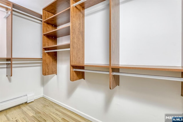 spacious closet featuring a baseboard heating unit and light hardwood / wood-style floors