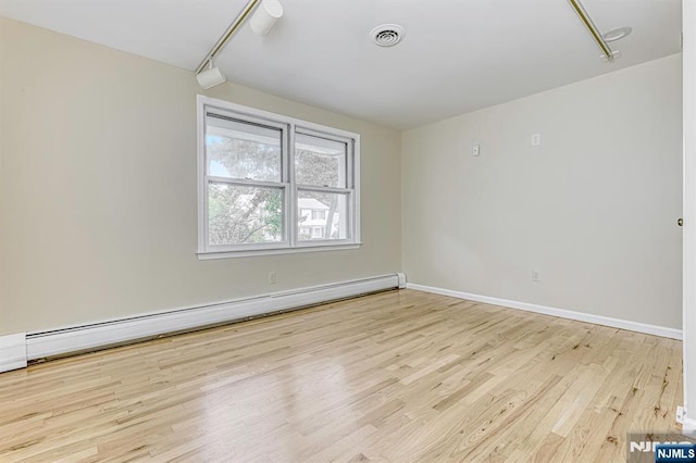 empty room with baseboard heating and light hardwood / wood-style floors