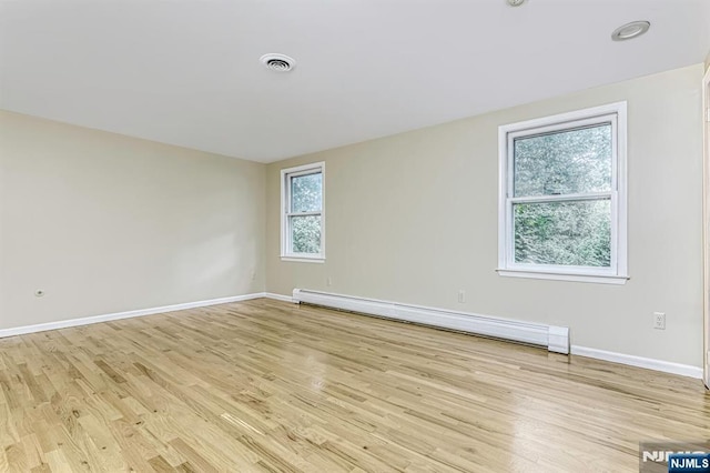 empty room with light hardwood / wood-style floors and a baseboard heating unit