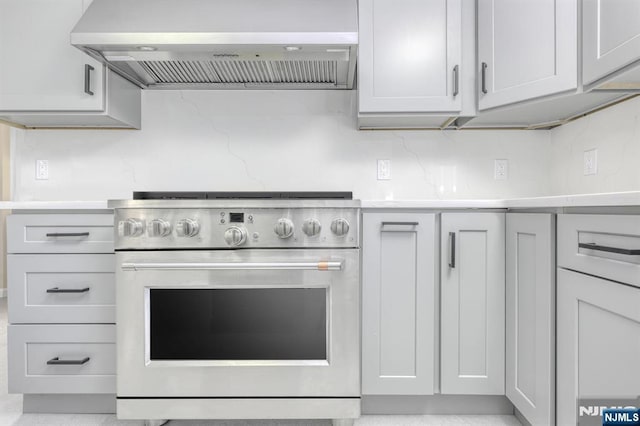 kitchen with tasteful backsplash, stainless steel range, and wall chimney exhaust hood