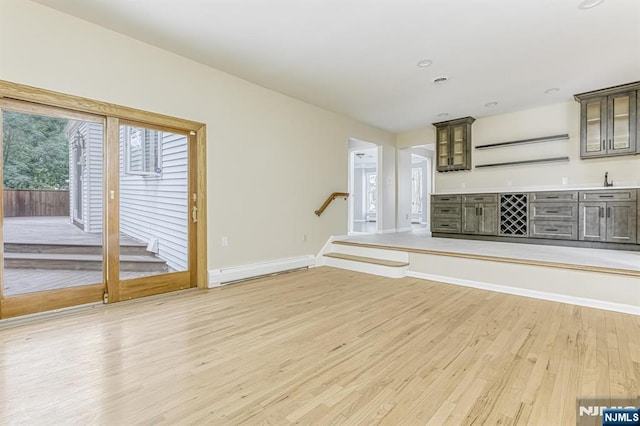 unfurnished living room featuring bar, a baseboard heating unit, and hardwood / wood-style flooring