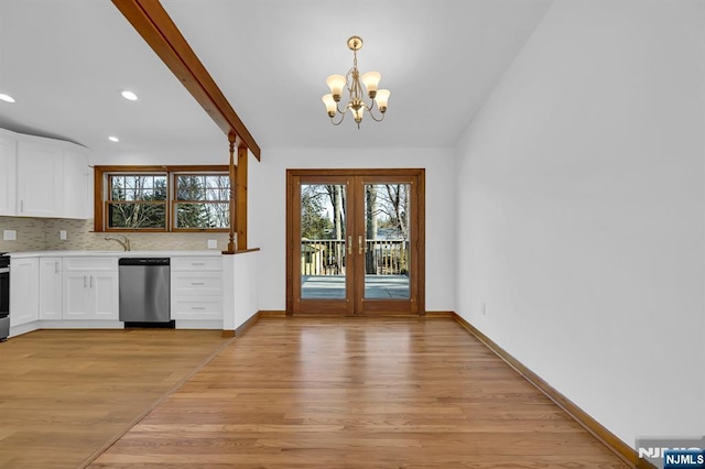 kitchen featuring dishwasher, white cabinetry, decorative light fixtures, french doors, and light wood-type flooring