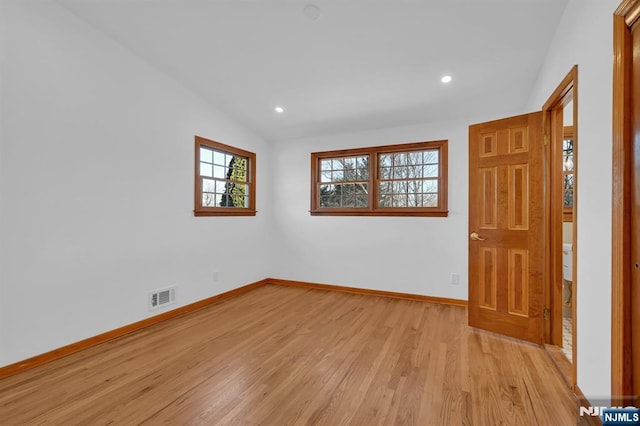 spare room with lofted ceiling and light hardwood / wood-style flooring