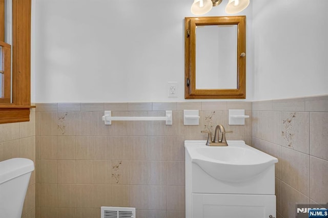 bathroom with vanity, tile walls, and toilet