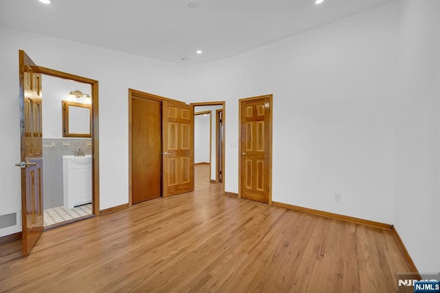 unfurnished bedroom with connected bathroom and light hardwood / wood-style floors