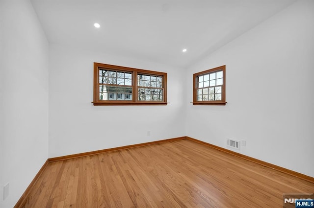 spare room with vaulted ceiling and light hardwood / wood-style floors