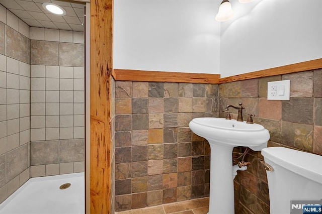 bathroom featuring tile walls, toilet, and tiled shower