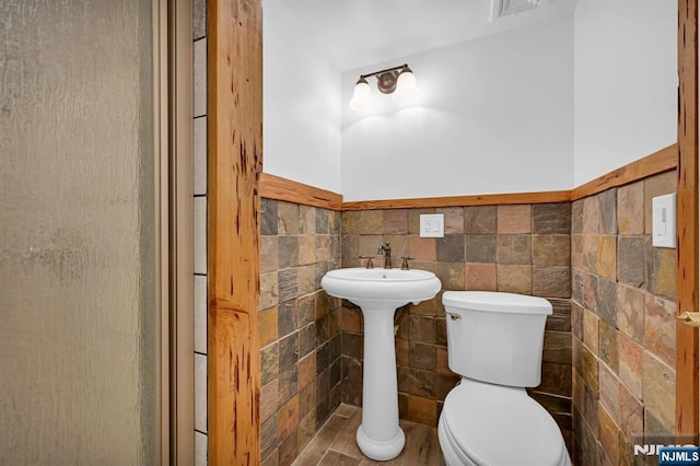 bathroom with tile walls and toilet