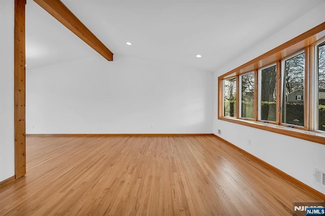 empty room featuring lofted ceiling with beams and light hardwood / wood-style flooring