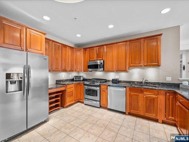 kitchen with dark stone countertops, sink, light tile patterned floors, and appliances with stainless steel finishes