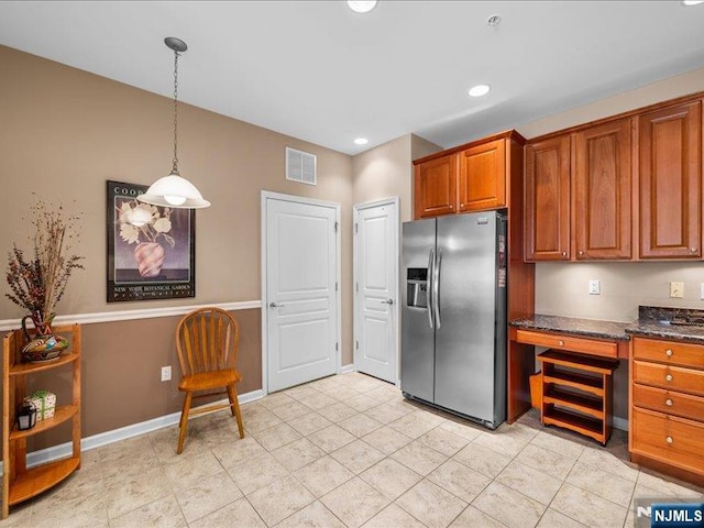 kitchen featuring pendant lighting, dark stone counters, and stainless steel fridge with ice dispenser