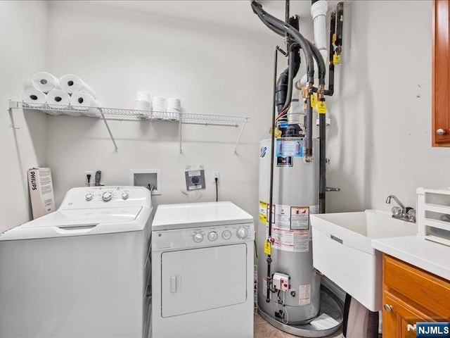 laundry area with cabinets, sink, washing machine and clothes dryer, and water heater