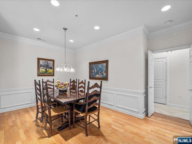 dining space featuring crown molding, a notable chandelier, and light hardwood / wood-style floors