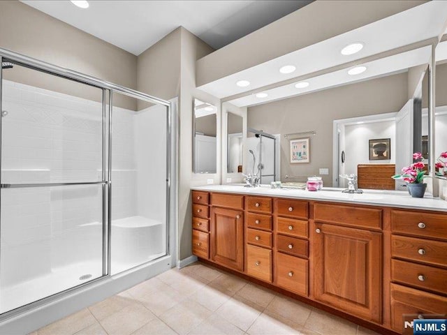 bathroom featuring a shower with door and vanity