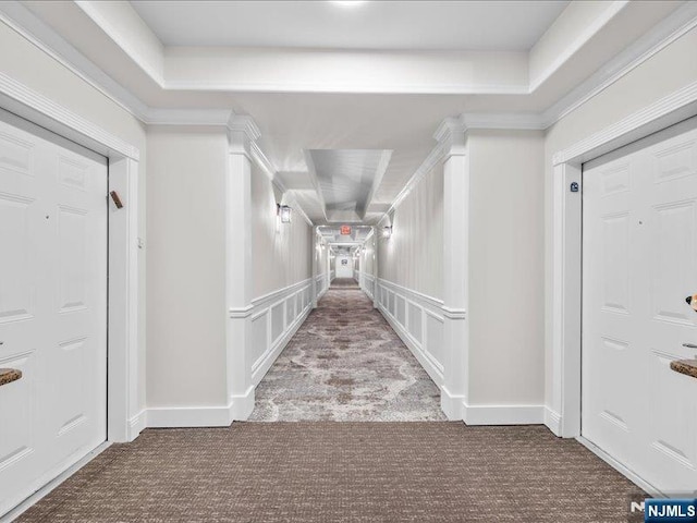 hallway featuring a tray ceiling, carpet floors, and ornamental molding