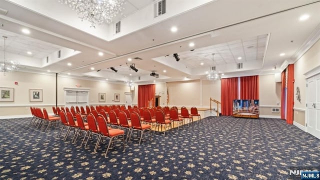 carpeted home theater featuring a raised ceiling, ornamental molding, and a notable chandelier