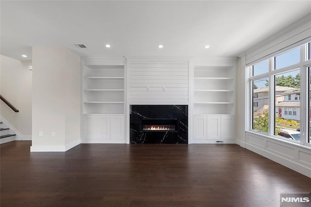 unfurnished living room with a fireplace, dark hardwood / wood-style flooring, and built in features