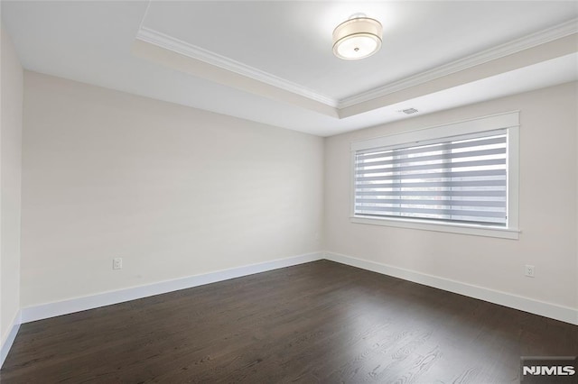 empty room featuring dark wood-type flooring, ornamental molding, and a tray ceiling