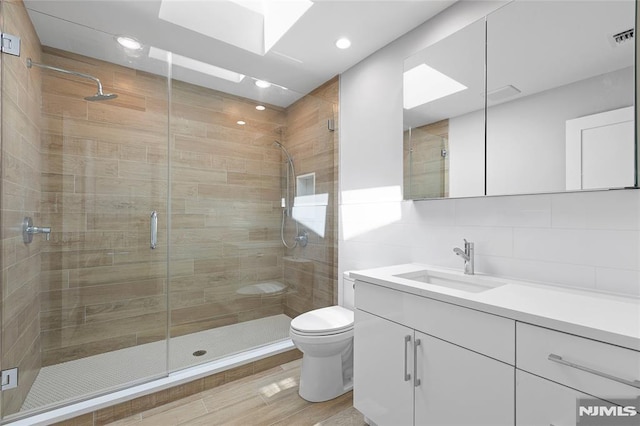 bathroom with vanity, an enclosed shower, a skylight, and toilet