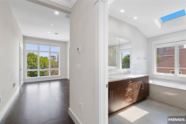 bathroom with vanity, hardwood / wood-style flooring, and vaulted ceiling with skylight