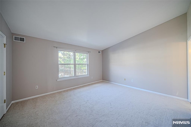 carpeted empty room featuring vaulted ceiling