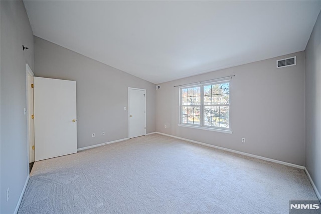 spare room with light colored carpet and vaulted ceiling