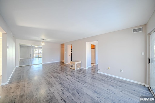 empty room with an inviting chandelier and wood-type flooring