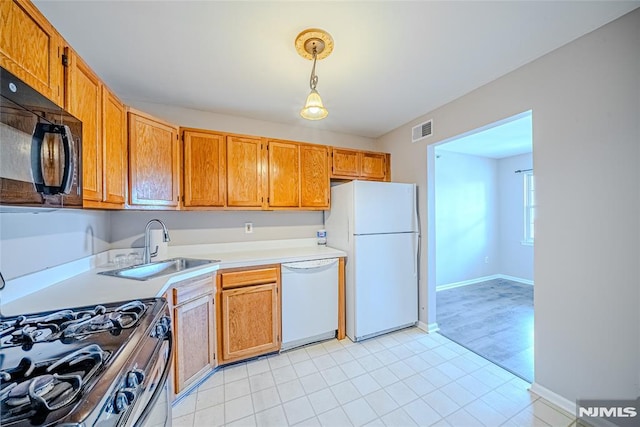 kitchen featuring white appliances, sink, and hanging light fixtures