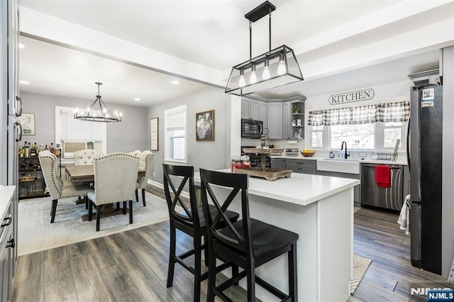 kitchen featuring sink, decorative light fixtures, appliances with stainless steel finishes, a kitchen breakfast bar, and gray cabinets