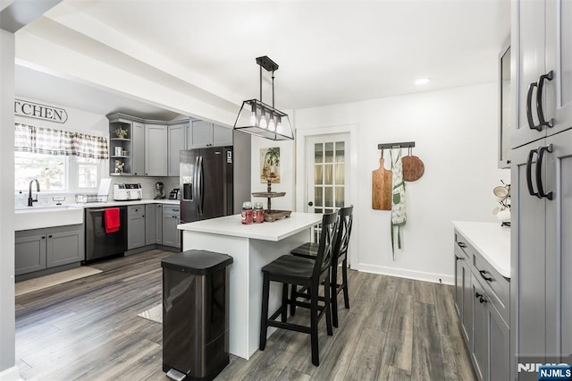 kitchen featuring gray cabinets, pendant lighting, a breakfast bar area, stainless steel appliances, and dark wood-type flooring