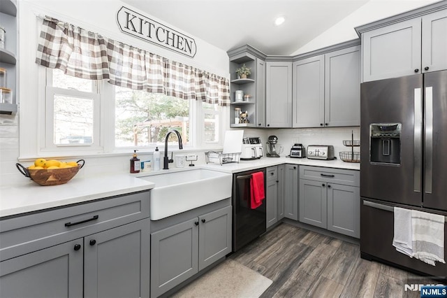 kitchen with stainless steel refrigerator with ice dispenser, lofted ceiling, sink, gray cabinetry, and dishwashing machine