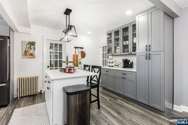 kitchen featuring gray cabinetry, dark hardwood / wood-style flooring, decorative light fixtures, and radiator heating unit