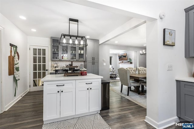 kitchen with hanging light fixtures, dark hardwood / wood-style floors, gray cabinetry, and decorative backsplash