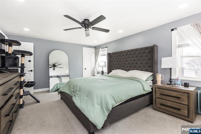 bedroom featuring multiple windows, radiator heating unit, light carpet, and ceiling fan