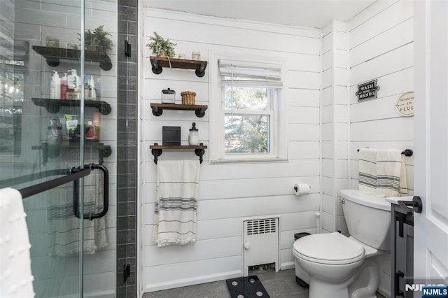 bathroom with a shower with door, radiator, and toilet