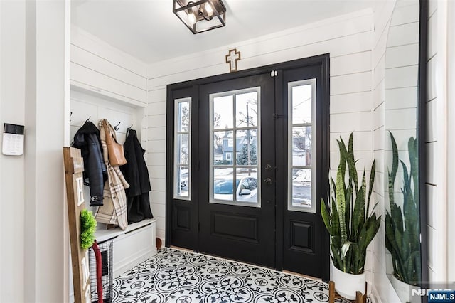 interior space with light tile patterned floors, french doors, and wood walls