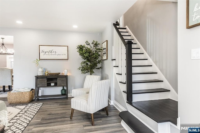 stairway with hardwood / wood-style floors and a chandelier