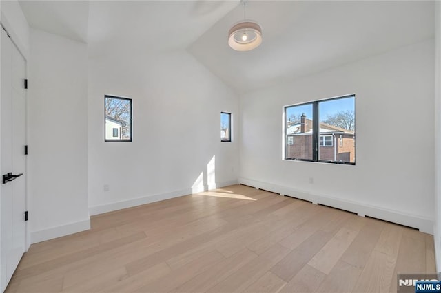 spare room with lofted ceiling and light hardwood / wood-style flooring