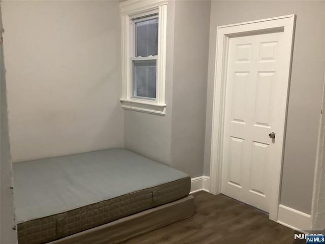 unfurnished bedroom with dark wood-type flooring and a closet