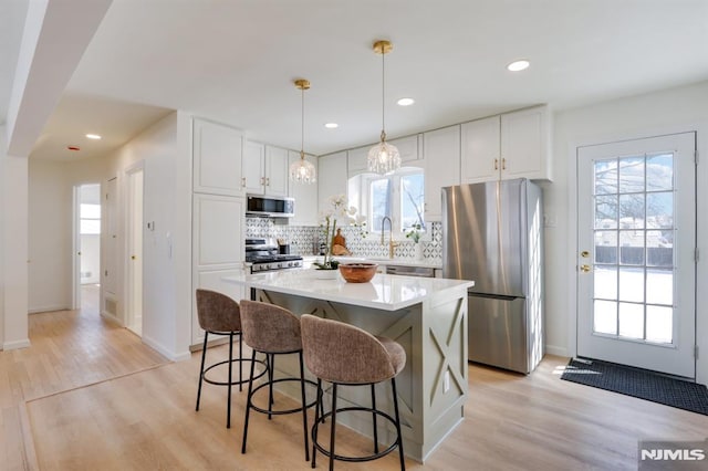 kitchen featuring light hardwood / wood-style flooring, stainless steel appliances, a center island, and white cabinets