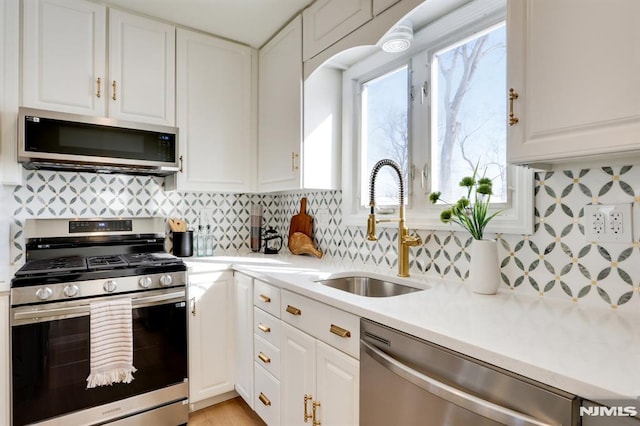 kitchen featuring stainless steel appliances, white cabinetry, tasteful backsplash, and sink