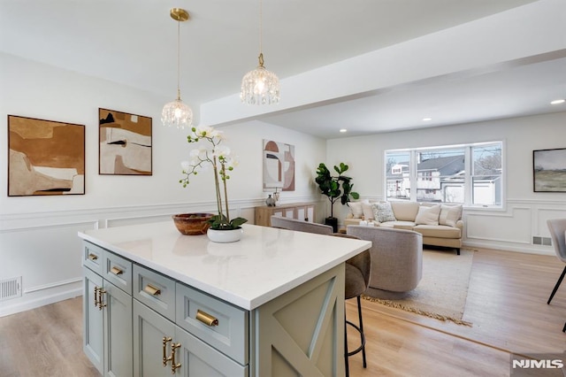 kitchen with pendant lighting, a breakfast bar area, gray cabinets, a center island, and light wood-type flooring