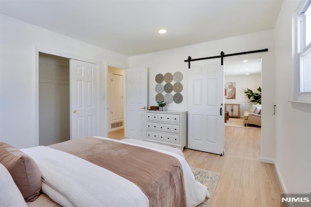 bedroom featuring a closet, a barn door, and light wood-type flooring