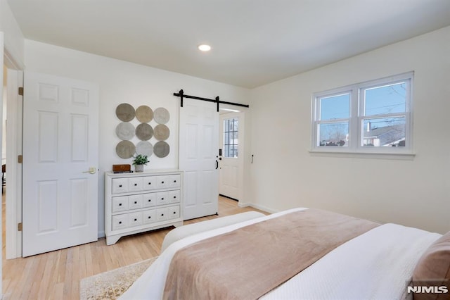 bedroom featuring a barn door and light hardwood / wood-style floors