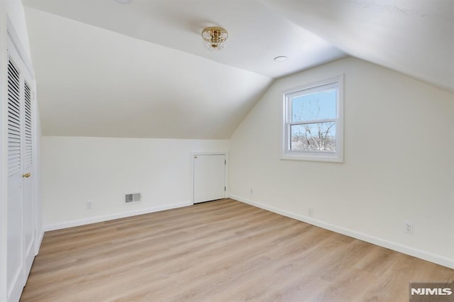 bonus room with lofted ceiling and light wood-type flooring