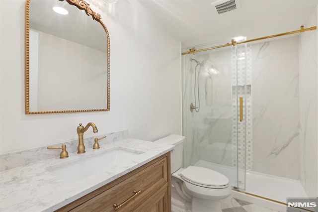 bathroom featuring vanity, an enclosed shower, and toilet