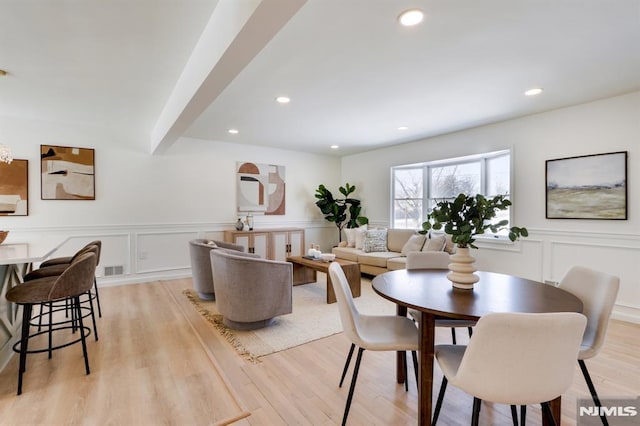 dining space with beam ceiling and light wood-type flooring