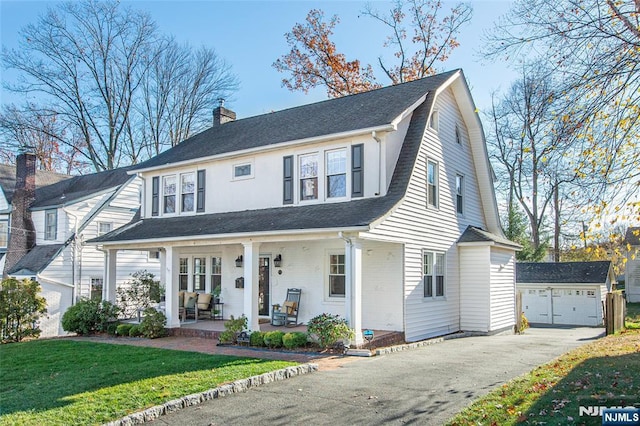 view of front of home featuring an outbuilding, a garage, covered porch, and a front yard