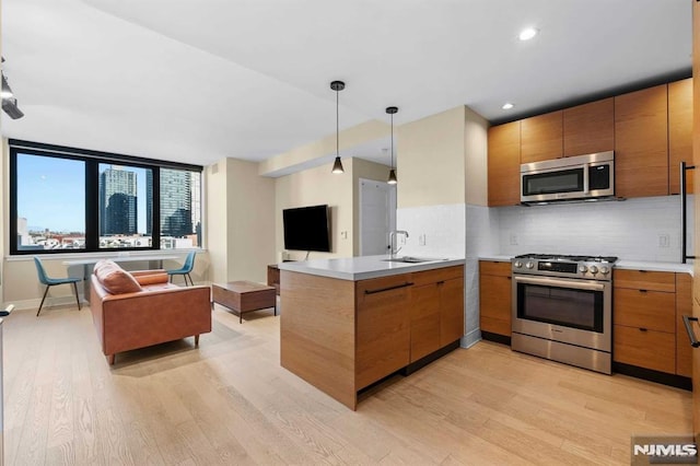 kitchen featuring stainless steel appliances, backsplash, light hardwood / wood-style floors, and kitchen peninsula