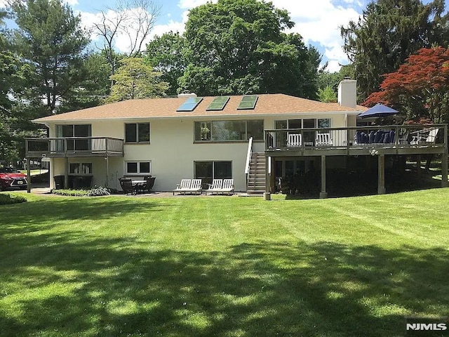 back of property with a lawn and a deck